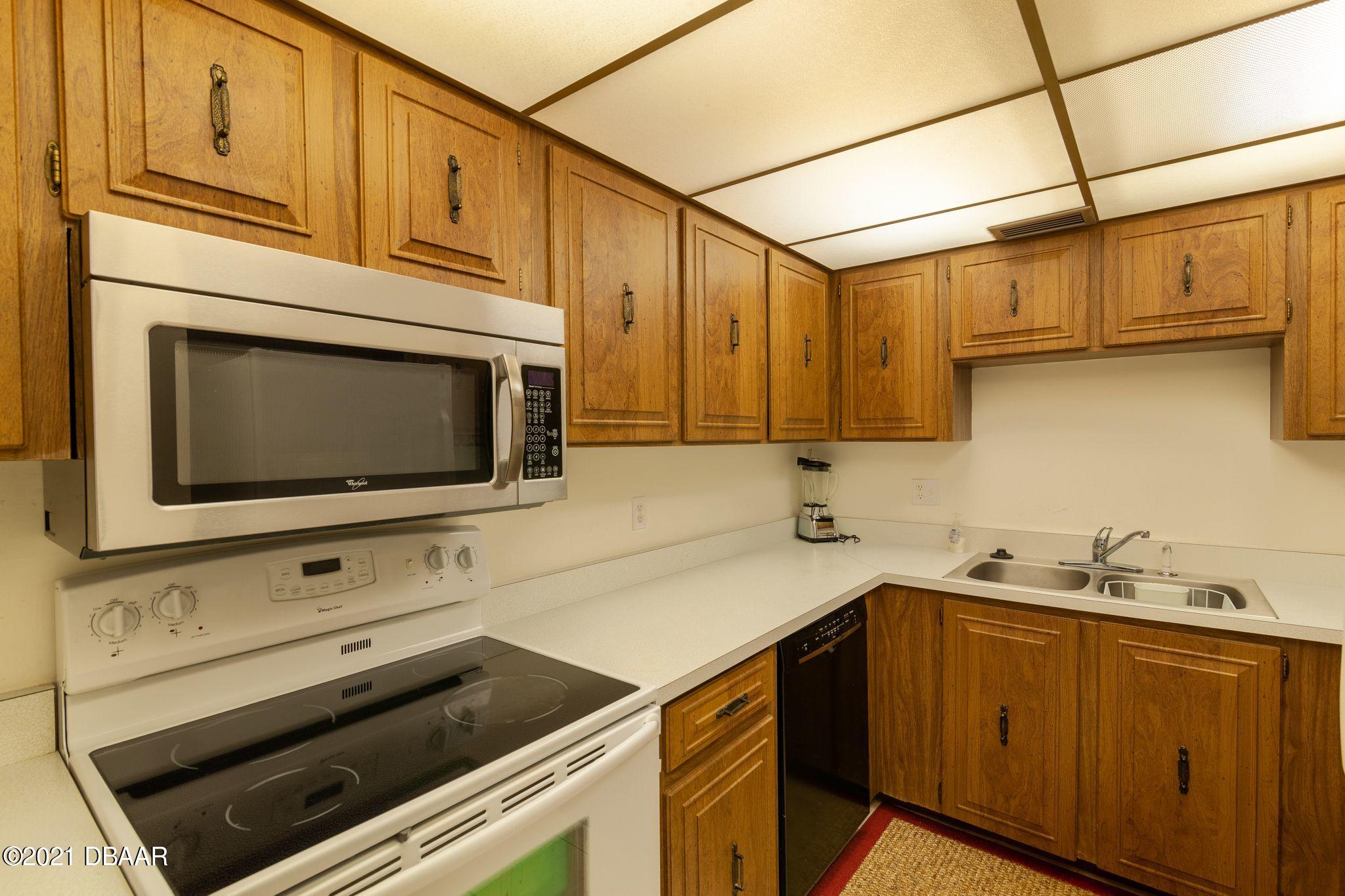 1415 Ocean Shore Boulevard, Unit 903 Ormond Beach, FL 32176 - Photo 9 of 47 a kitchen with stainless steel appliances a stove microwave and cabinets