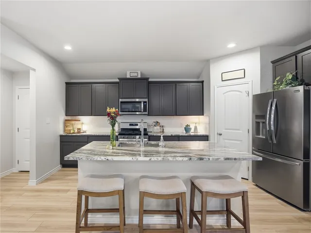 a kitchen with kitchen island granite countertop a refrigerator stove microwave and sink