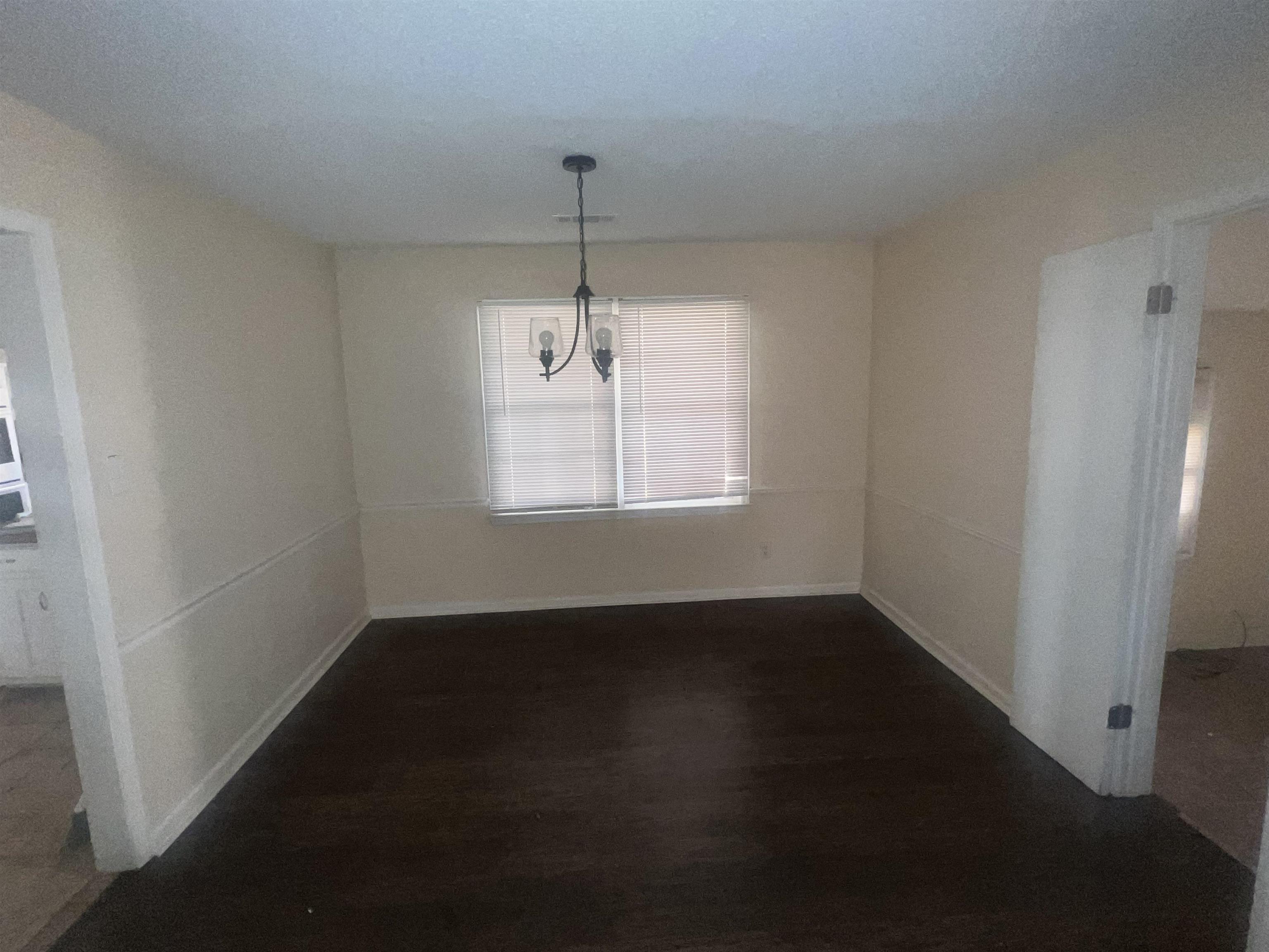 4295 Hudgins Road Memphis, TN 38116 - Photo 2 of 16 Spacious room featuring dark wood-finish flooring, light-toned walls with chair rail molding, and a central chandelier