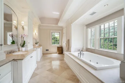 a large white tub sitting in a bathroom next to a window
