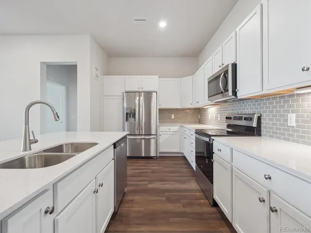 a kitchen with white cabinets a sink and stainless steel appliances
