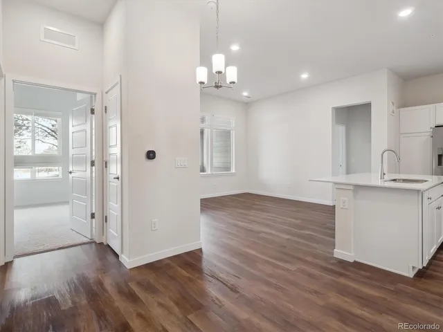 a view of a hallway with wooden floor and a kitchen