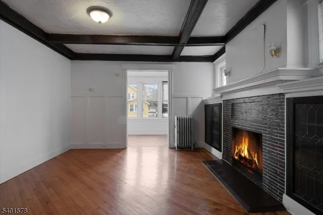 a view of an empty room with wooden floor fireplace and a window