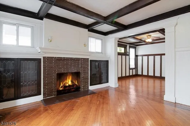 a view of an empty room with wooden floor fireplace and a window