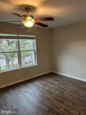an empty room with wooden floor chandelier and windows