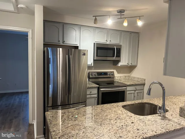 a kitchen with granite countertop a refrigerator and a stove top oven