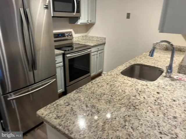 a kitchen with granite countertop a sink and a stainless steel appliances
