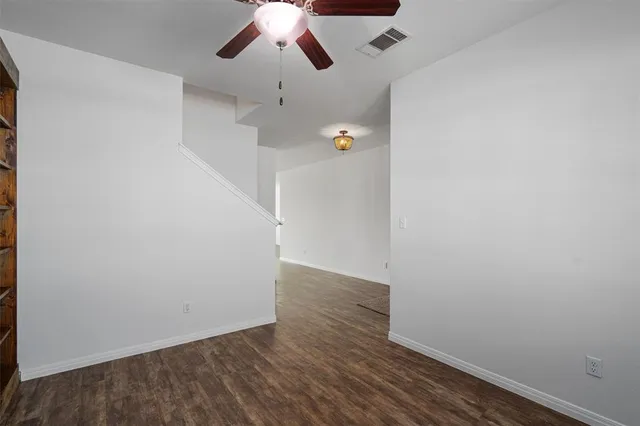 an empty room with wooden floor fan and window