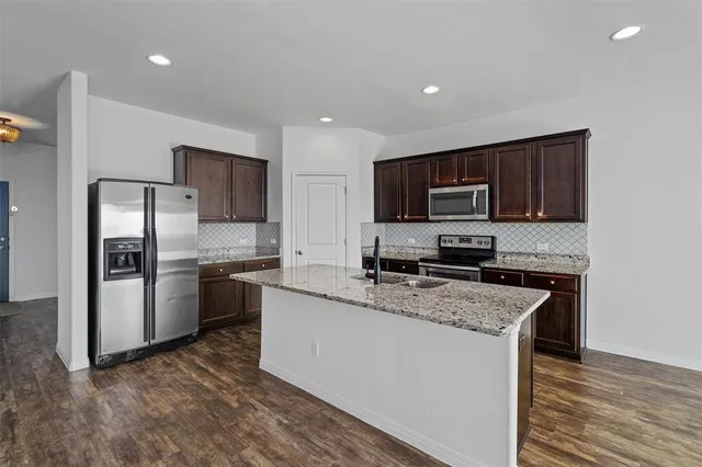 a kitchen with a refrigerator a microwave a sink and cabinets