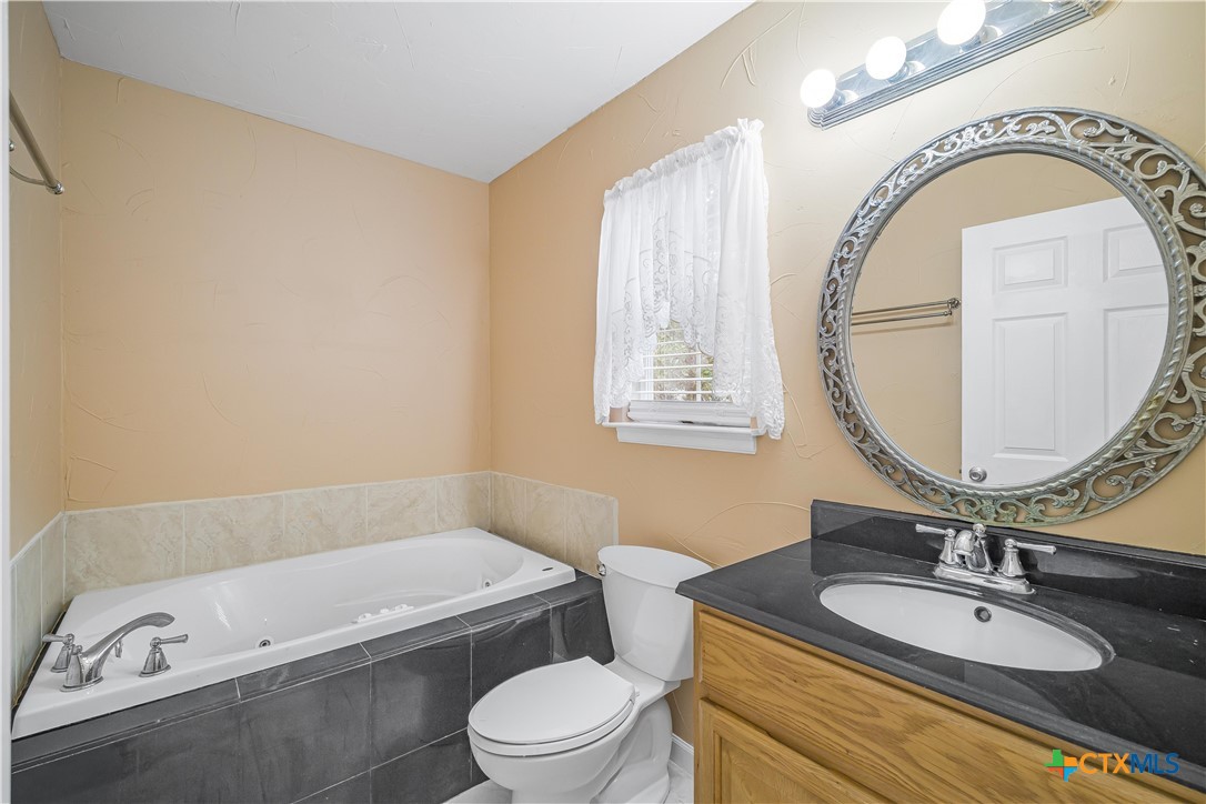 233 Post Oak Bend Inez, TX 77968 - Photo 41 of 45 a bathroom with a granite countertop toilet a sink and a mirror
