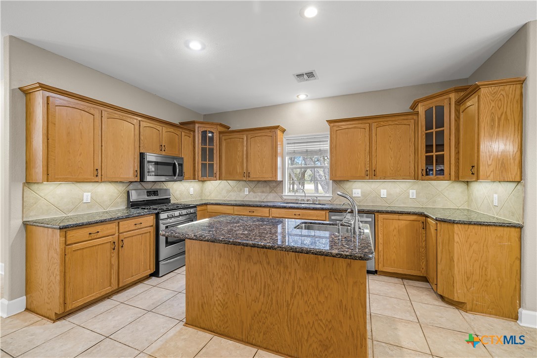 233 Post Oak Bend Inez, TX 77968 - Photo 10 of 45 a kitchen with stainless steel appliances granite countertop wooden cabinets a sink and dishwasher a stove top oven with wooden floor