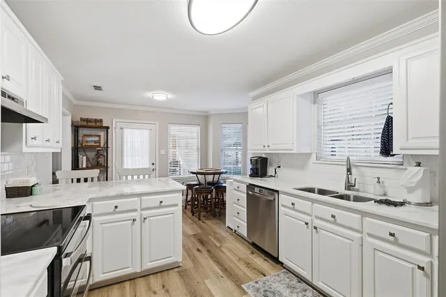 a kitchen with a sink stove cabinets and wooden floor