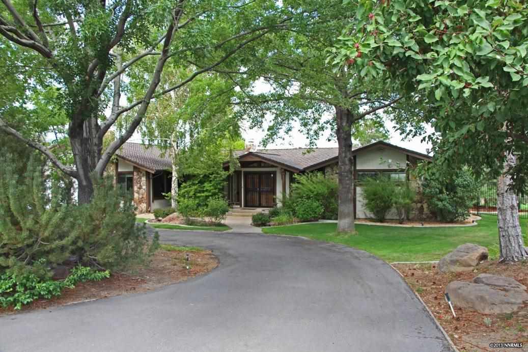 a front view of a house with a garden and trees