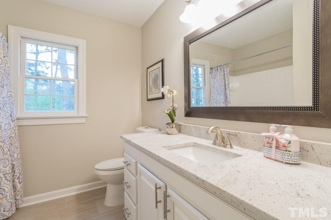 5505 Raddington Street Raleigh, NC 27613 - Photo 19 of 25 a bathroom with a granite countertop sink a toilet and a mirror