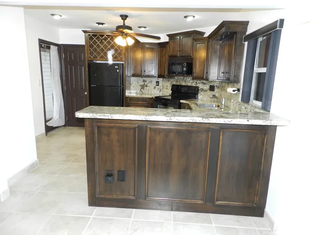 a kitchen with stainless steel appliances kitchen island granite countertop a refrigerator a sink and dishwasher