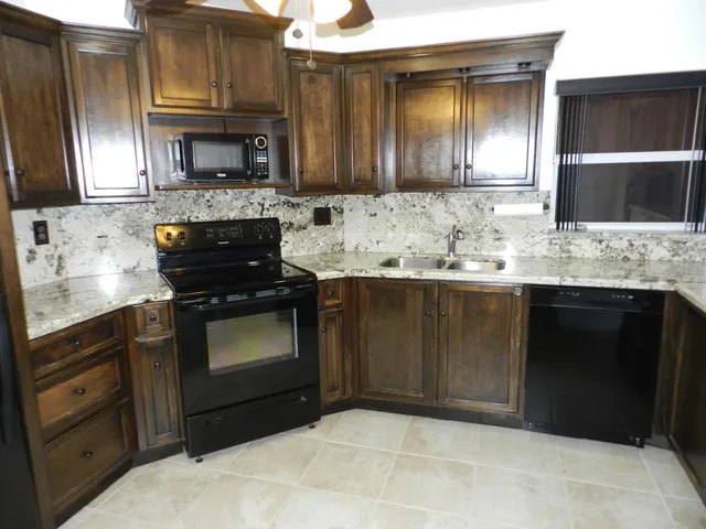 a kitchen with stainless steel appliances granite countertop a stove a sink and a microwave