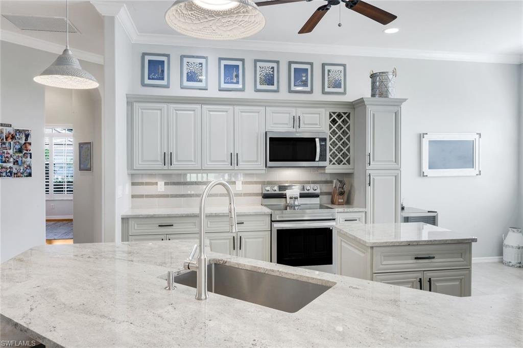 12694 Fox Ridge Drive Bonita Springs, FL 34135 - Photo 13 of 35 a kitchen with stainless steel appliances kitchen island granite countertop a stove and a sink