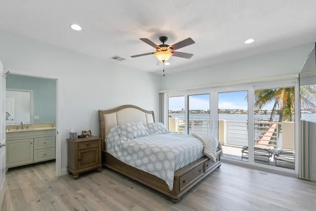 a bedroom with a bed and a large window with wooden floor