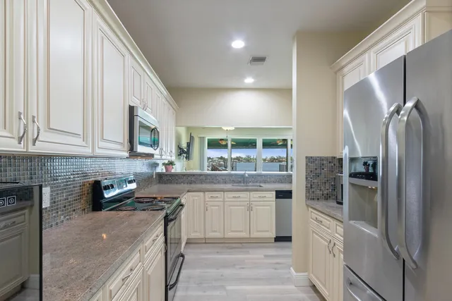 a kitchen with stainless steel appliances granite countertop a refrigerator a stove and a sink