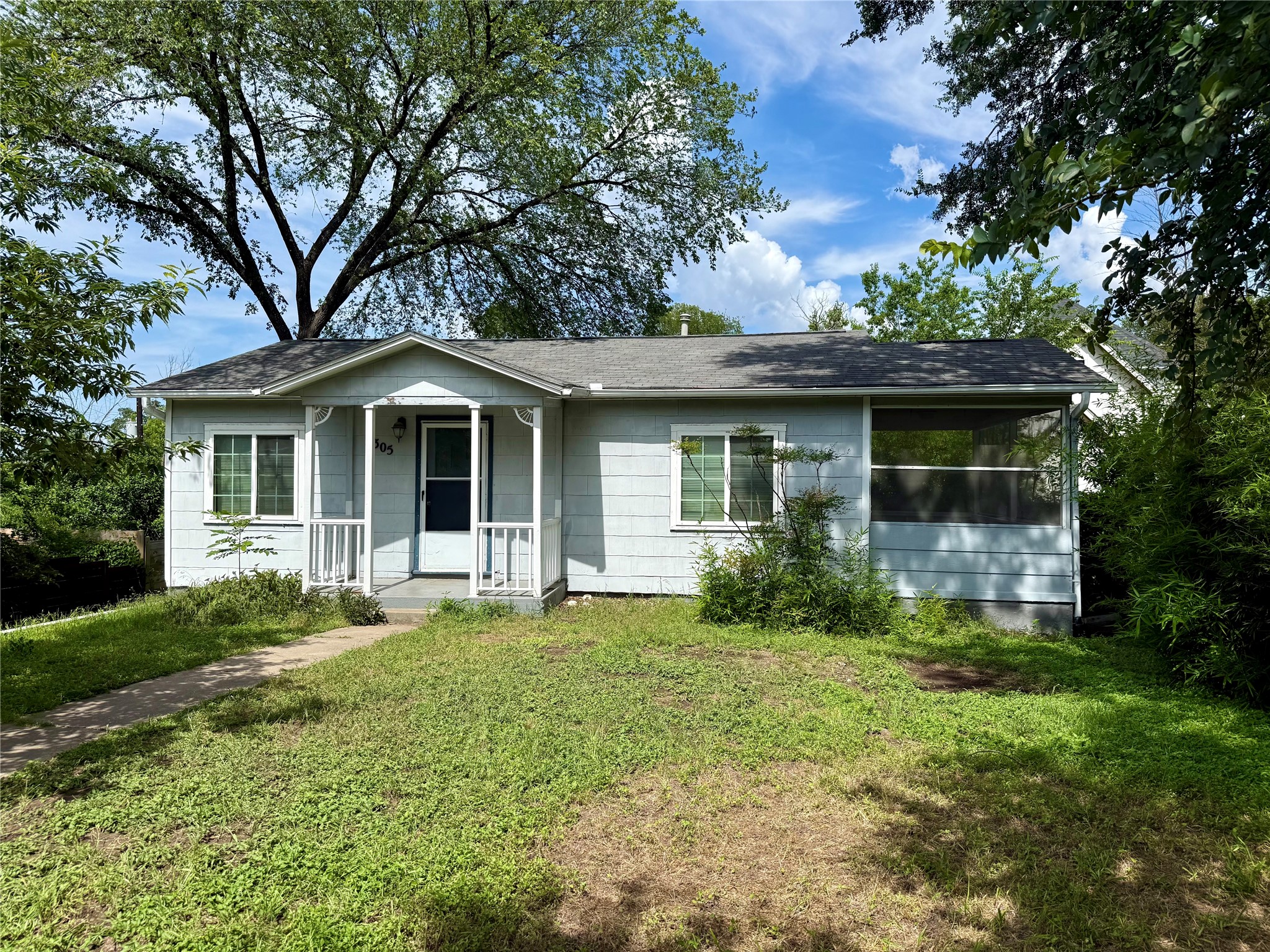 A charming single-story residence with a welcoming front porch and mature trees for ample shade.