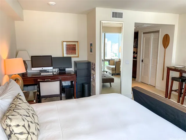 a bedroom with a bed and a computer on a desk next to a window