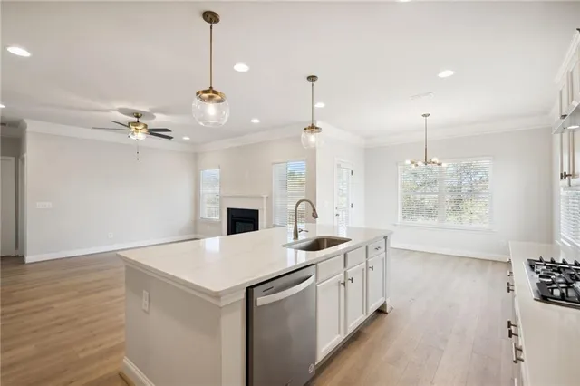 a kitchen with a sink a chandelier stainless steel appliances and cabinets