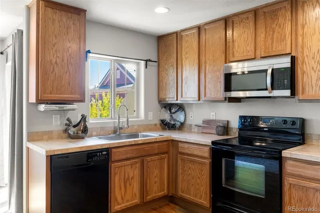 a kitchen with stainless steel appliances granite countertop white cabinets sink and a microwave