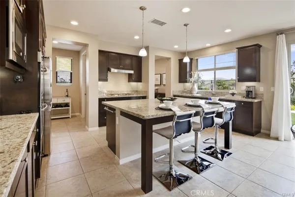 a kitchen with kitchen island granite countertop a sink a counter top stainless steel appliances and cabinets