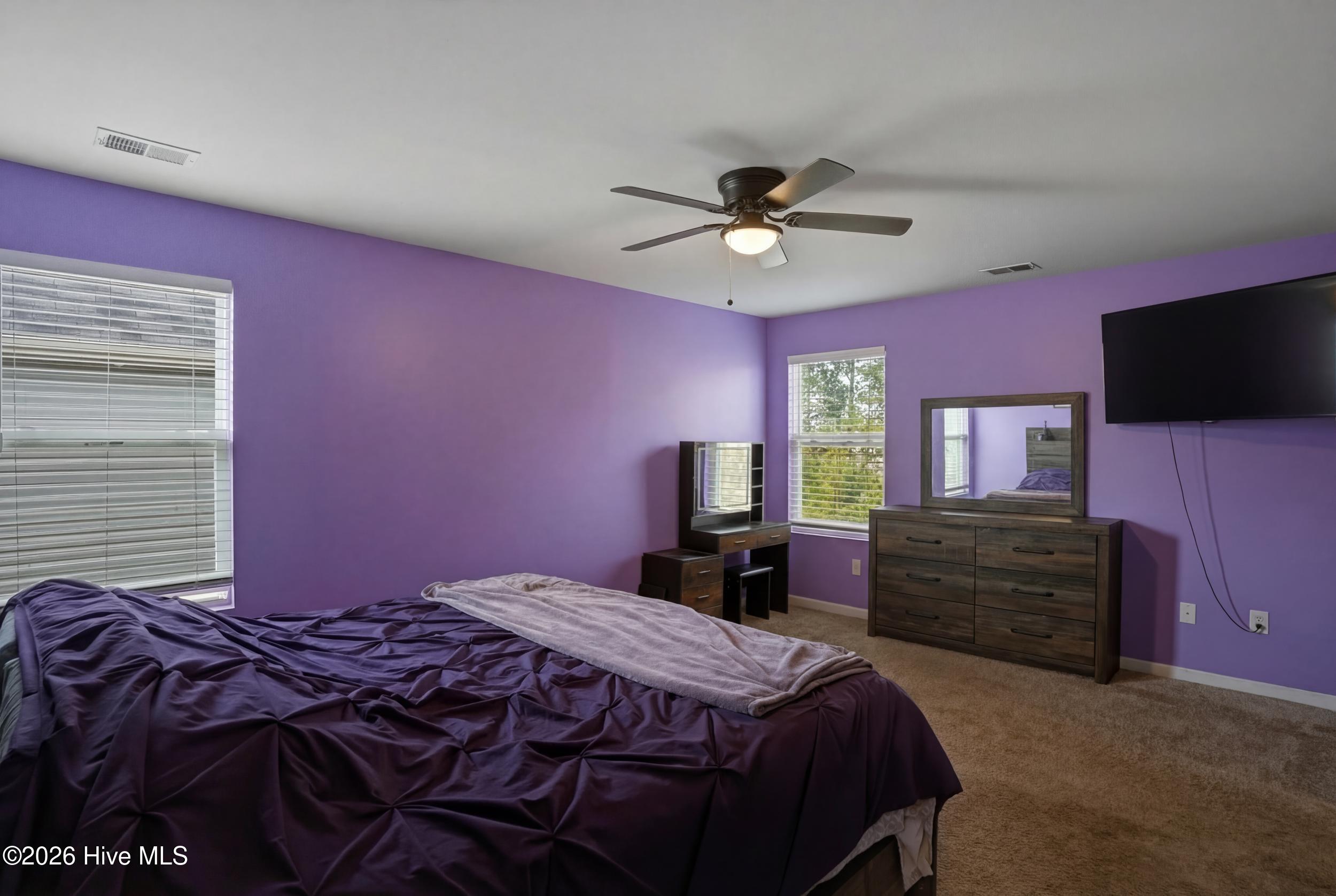 793 Landmark Cove Calabash, NC 28467 - Photo 24 of 53 Spacious primary bedroom with carpeted floors and ceiling fan, showcasing a bright and inviting atmosphere.