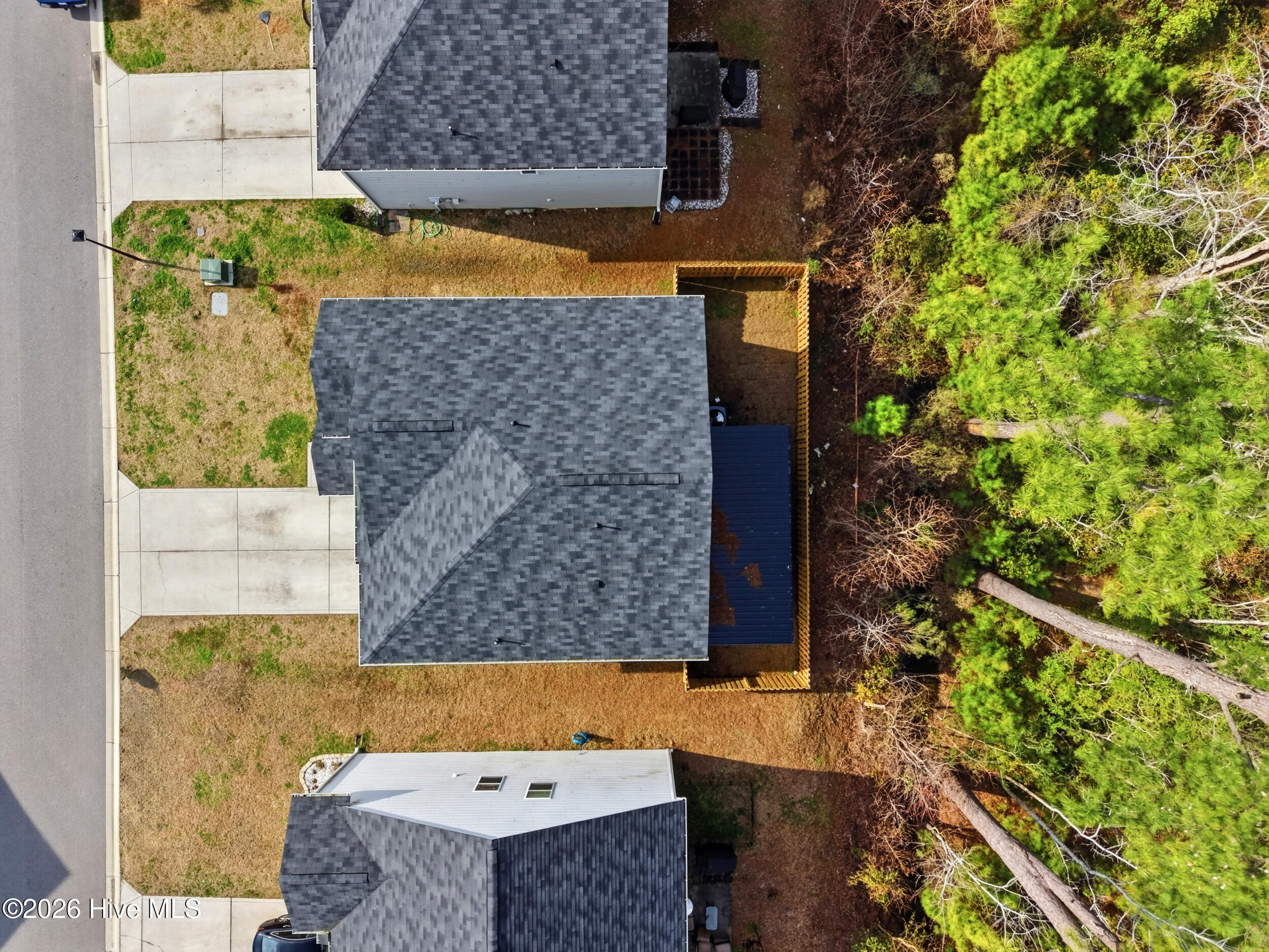 793 Landmark Cove Calabash, NC 28467 - Photo 44 of 53 Drone view looking down at the home’s roof and backyard, showcasing the spacious outdoor area backing up to the wood line for added privacy and natural surroundings.