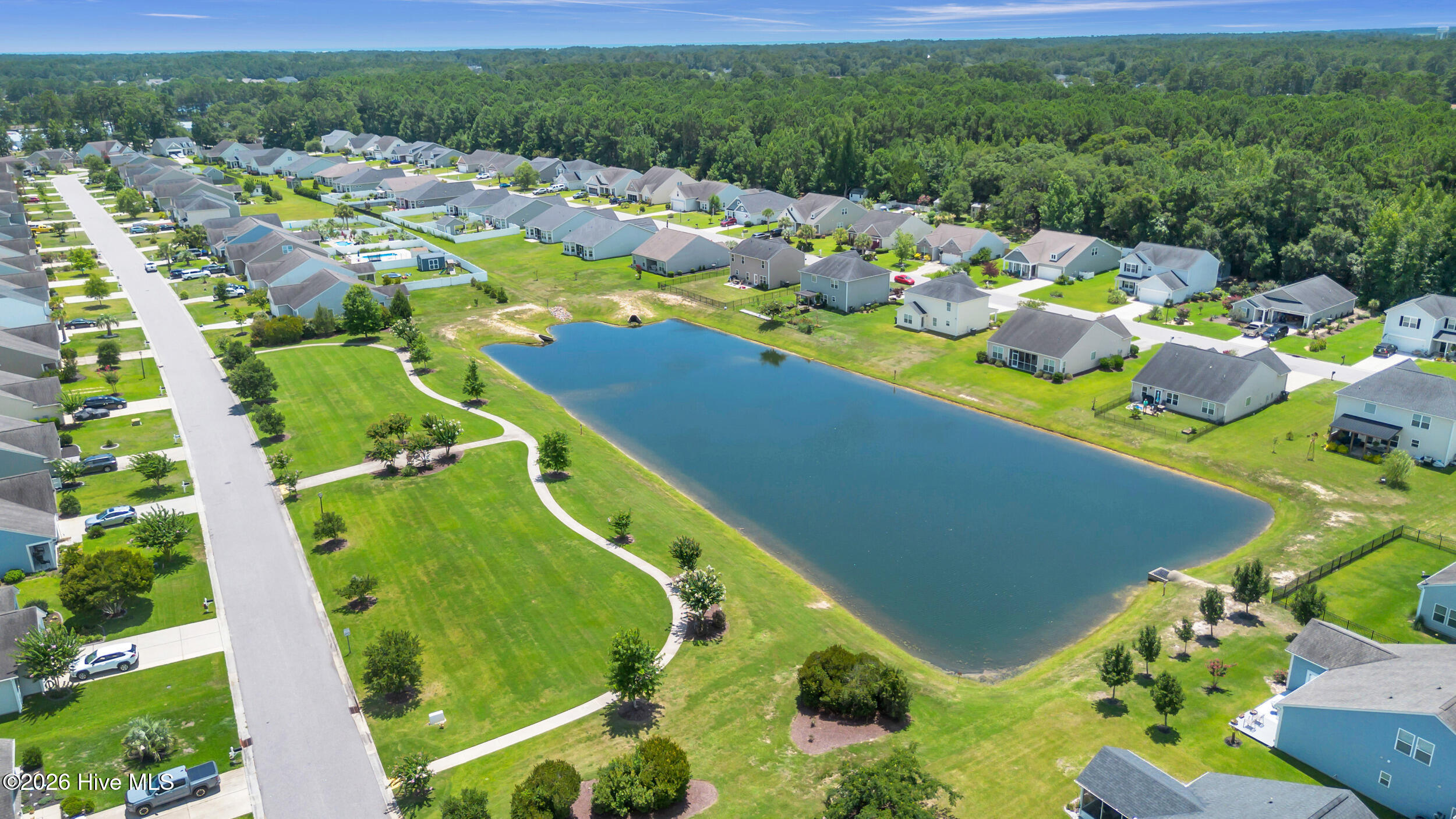 793 Landmark Cove Calabash, NC 28467 - Photo 52 of 53 Expansive neighborhood green space offering a serene and open area for outdoor enjoyment within the community.