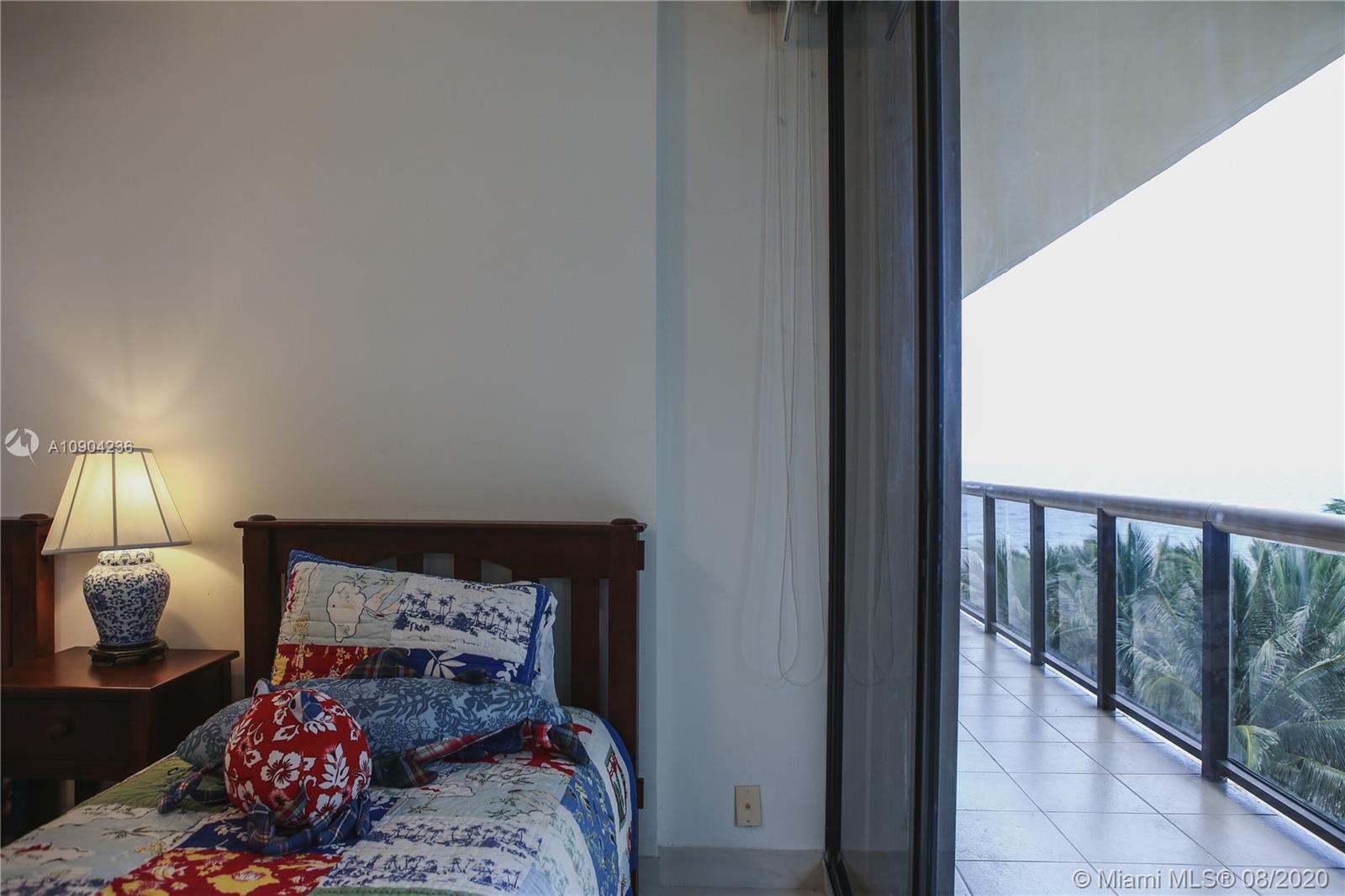 9455 Collins Avenue, Unit 707 Surfside, FL 33154 - Photo 20 of 60 a bedroom with a bed and a lamp on dresser