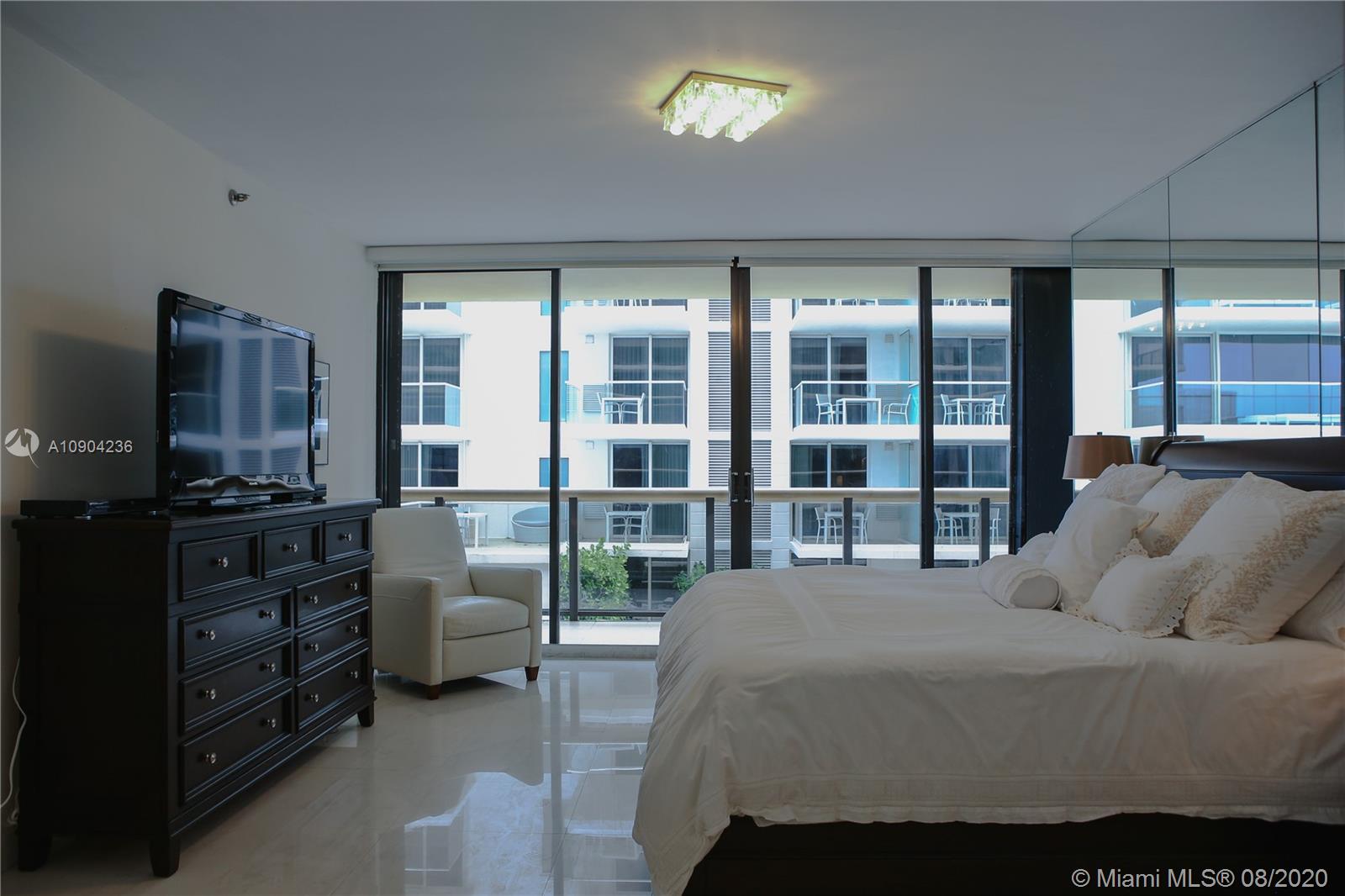 9455 Collins Avenue, Unit 707 Surfside, FL 33154 - Photo 26 of 60 a bedroom with a bed and large windows