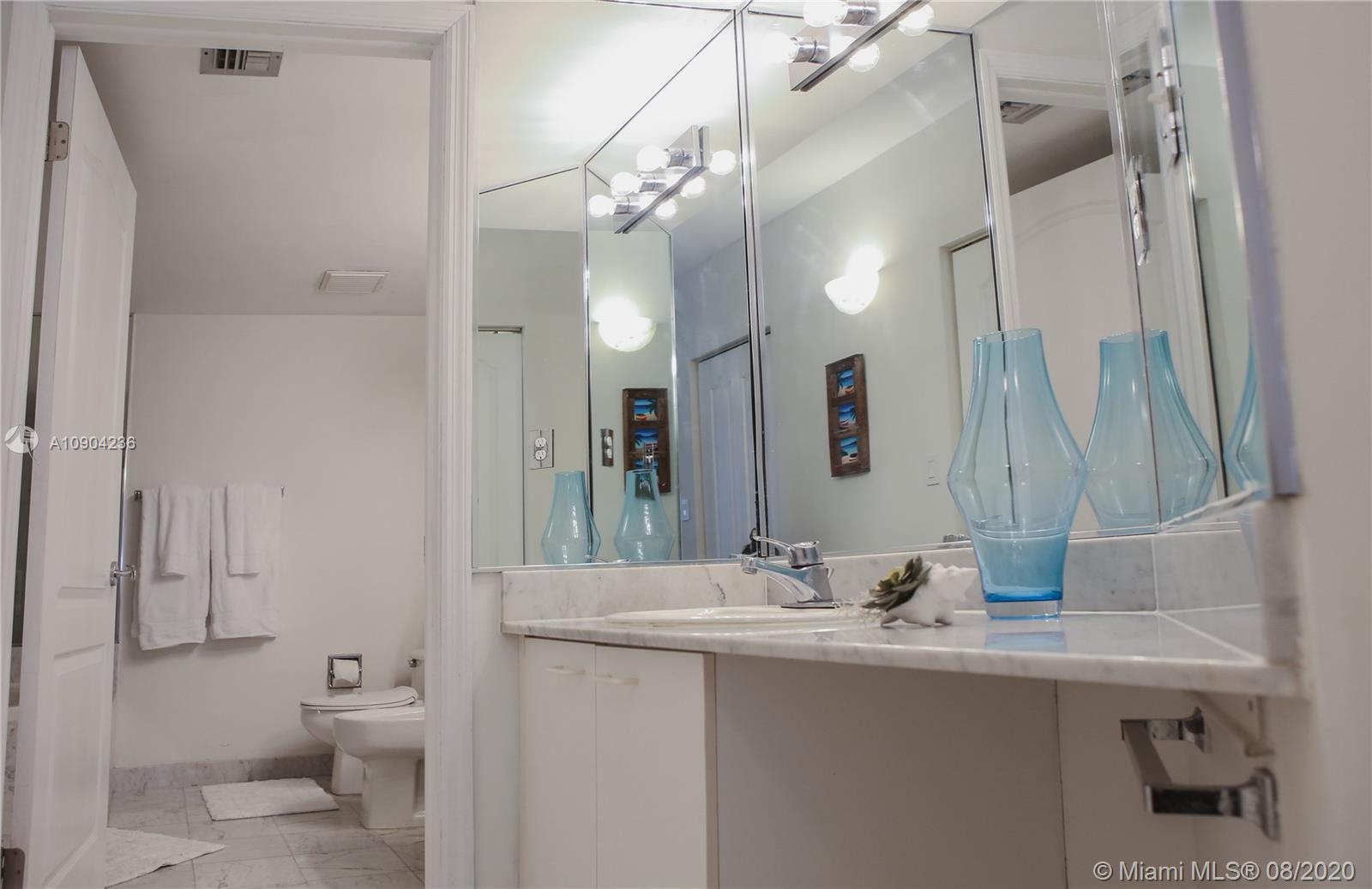 9455 Collins Avenue, Unit 707 Surfside, FL 33154 - Photo 30 of 60 a bathroom with a granite countertop sink a toilet and a large mirror