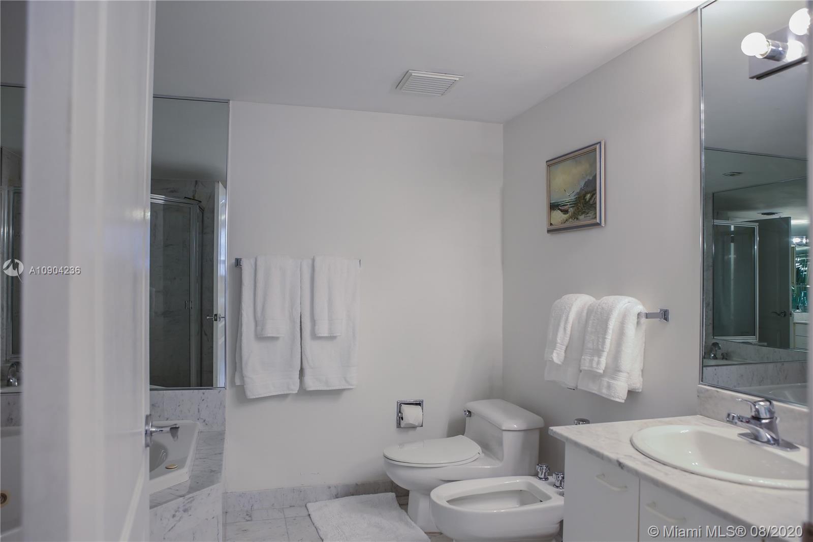 9455 Collins Avenue, Unit 707 Surfside, FL 33154 - Photo 31 of 60 a bathroom with a toilet sink and mirror