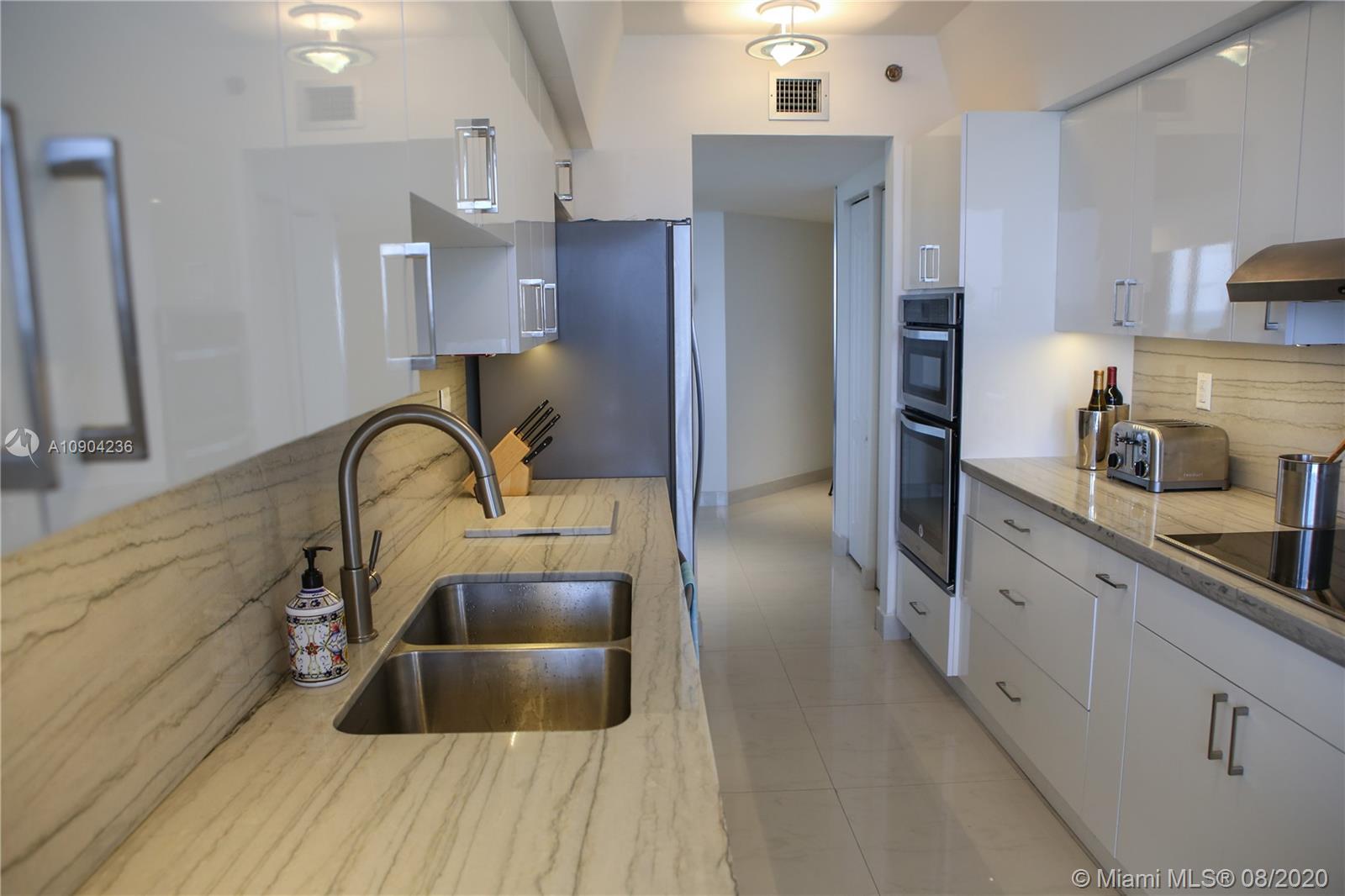 9455 Collins Avenue, Unit 707 Surfside, FL 33154 - Photo 41 of 60 a kitchen with stainless steel appliances a sink cabinets and wooden floor
