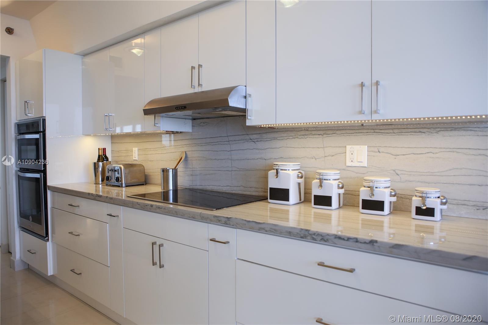9455 Collins Avenue, Unit 707 Surfside, FL 33154 - Photo 42 of 60 a kitchen with white cabinets and a sink