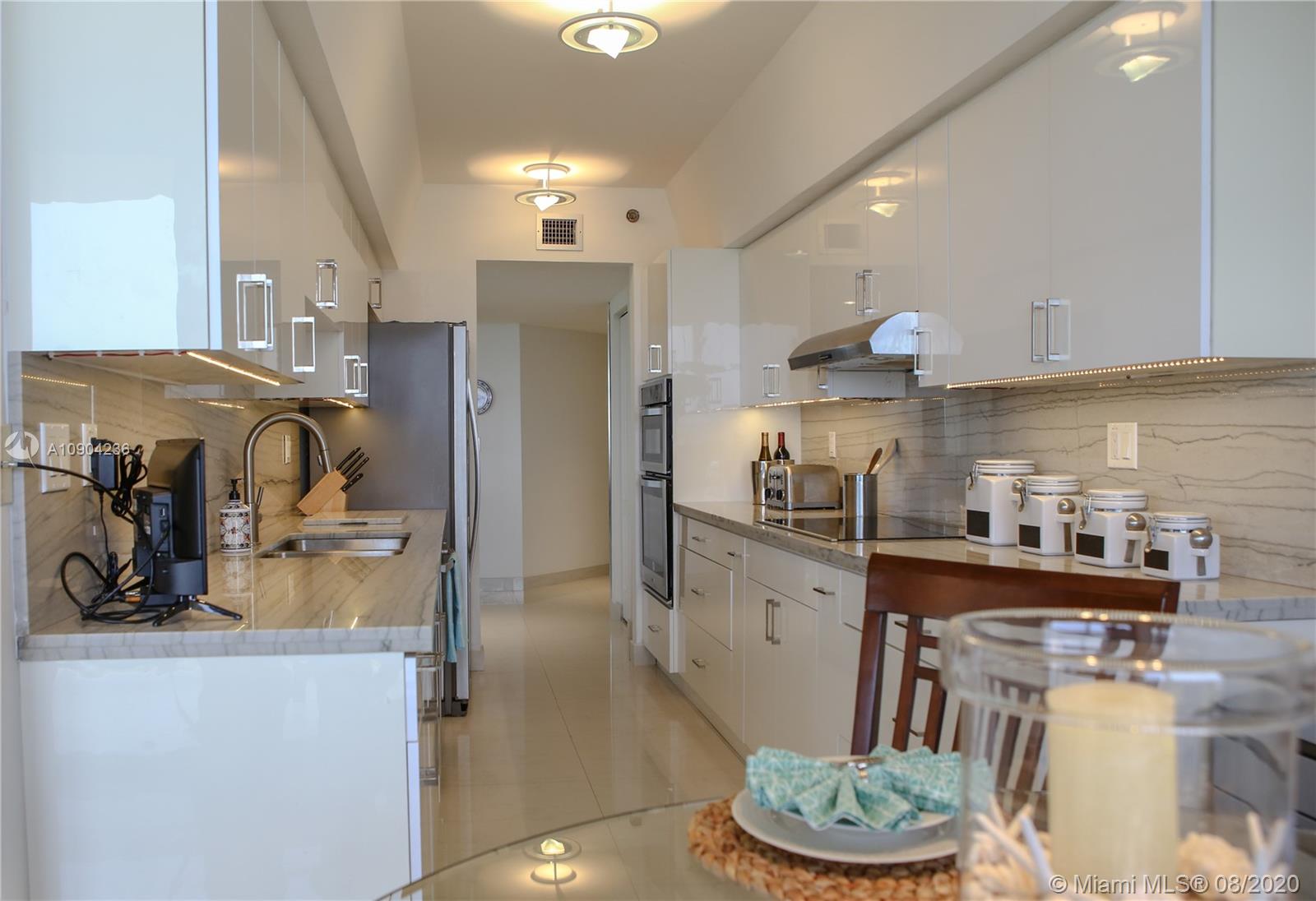 9455 Collins Avenue, Unit 707 Surfside, FL 33154 - Photo 45 of 60 a kitchen with stainless steel appliances granite countertop a sink refrigerator and cabinets