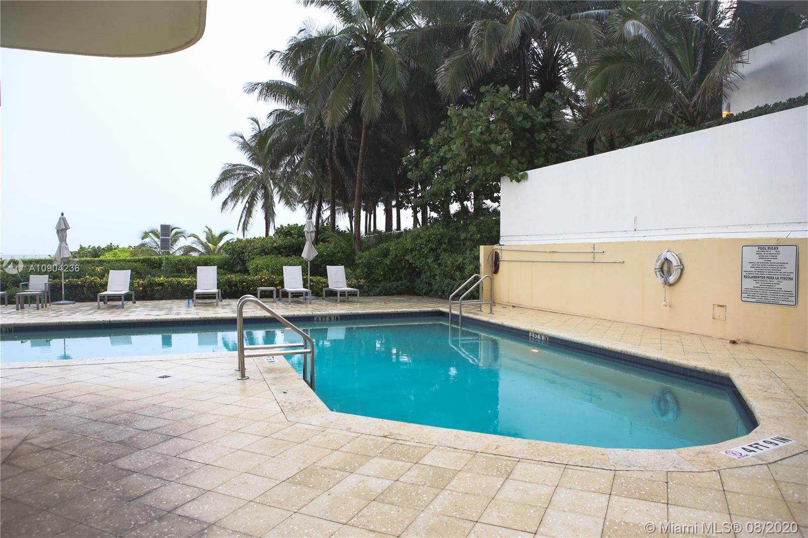 9455 Collins Avenue, Unit 707 Surfside, FL 33154 - Photo 50 of 60 a view of a swimming pool with a chair and tables