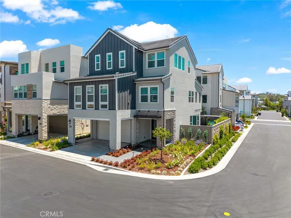a view of a white house with a small yard and potted plants