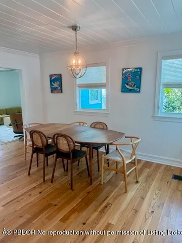 a dining room with wooden floor a chandelier a wooden table and chairs
