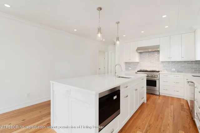 a kitchen with stainless steel appliances white cabinets and a stove top oven
