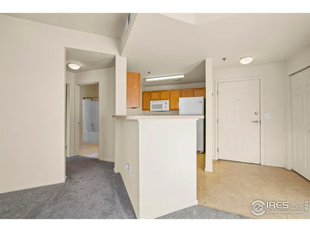 a view of a big room with wooden floor and a kitchen