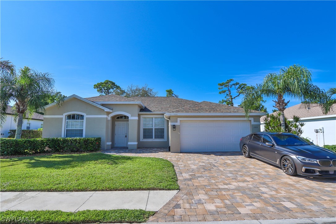 23351 Olde Meadowbrook Circle Estero, FL 34134 - Photo 2 of 25 a front view of a house with a garden and yard