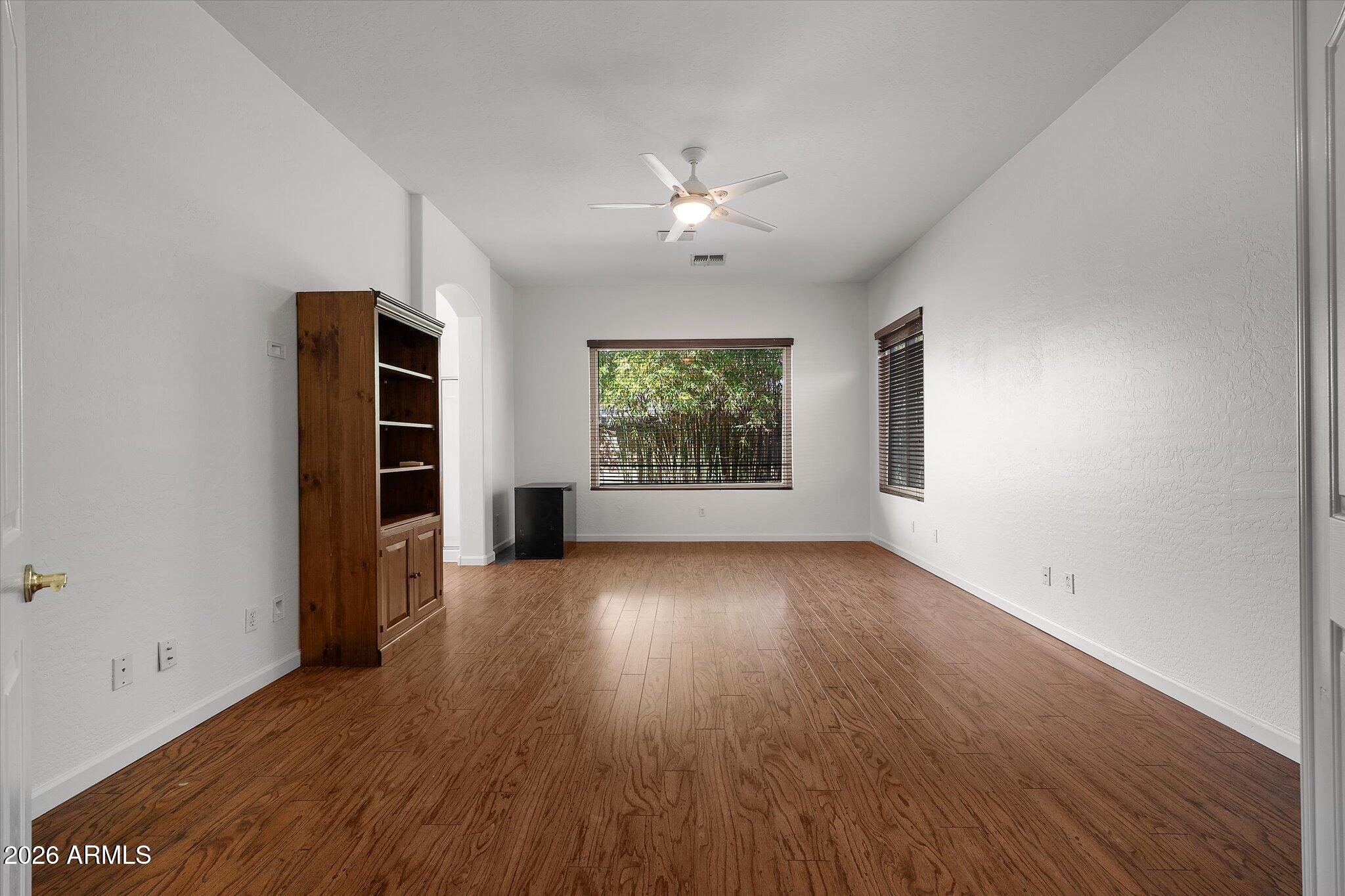 4018 East Harrison Street Gilbert, AZ 85295 - Photo 30 of 45 an empty room with wooden floor chandelier fan and windows