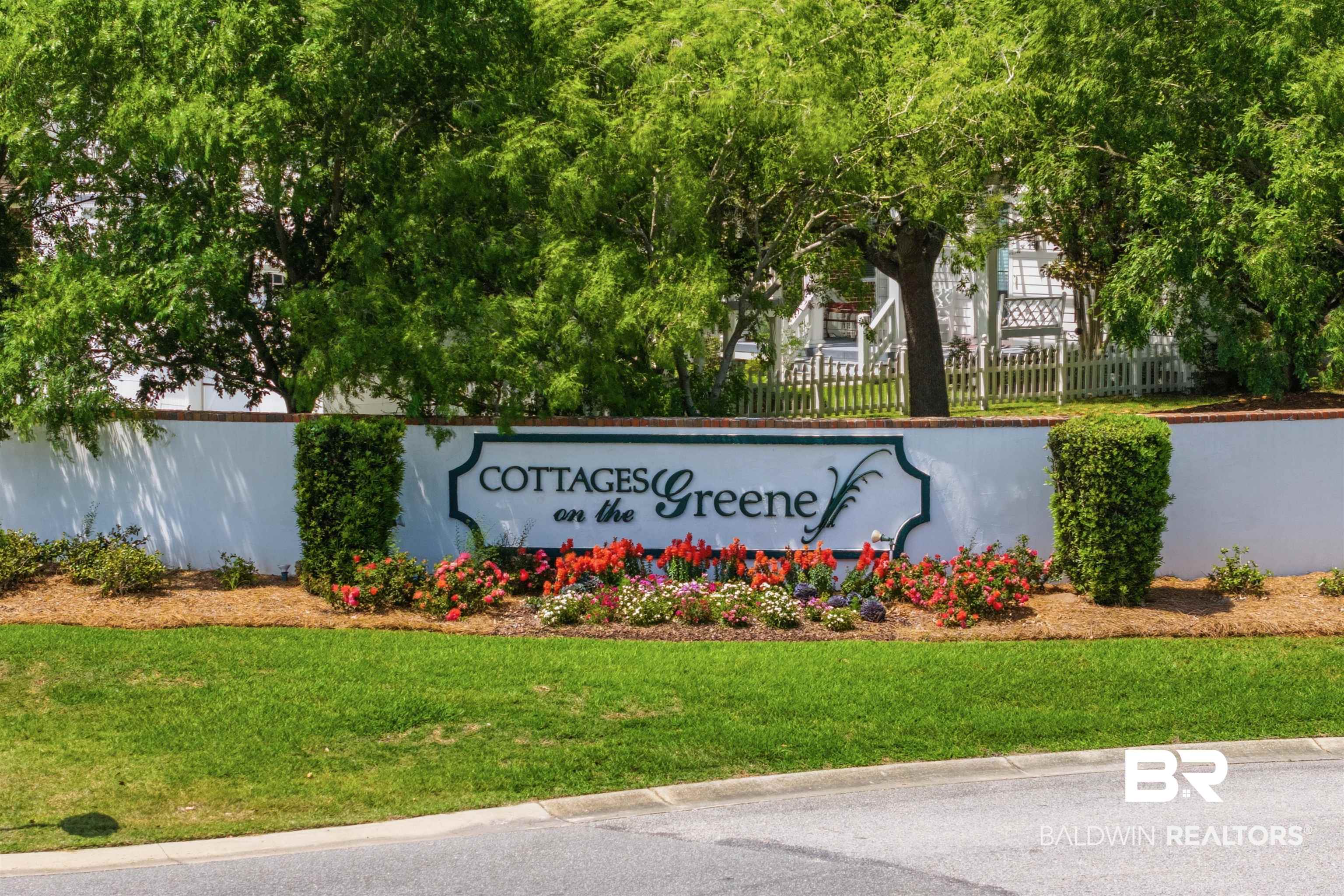 927 Periwinkle Lane Foley, AL 36535 - Photo 22 of 26 Community entrance featuring a white wall, custom signage, manicured landscaping, vibrant floral accents, and mature trees