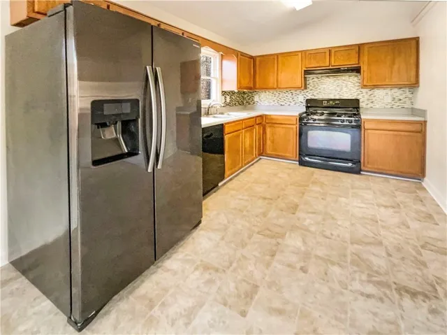 a kitchen with granite countertop a refrigerator stove and oven