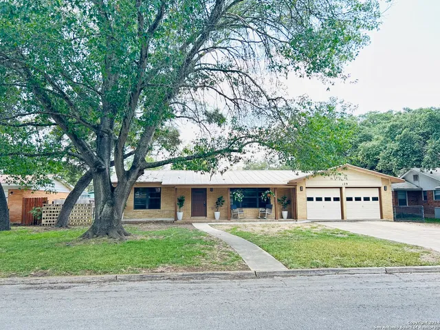 a front view of a house with a garden and trees