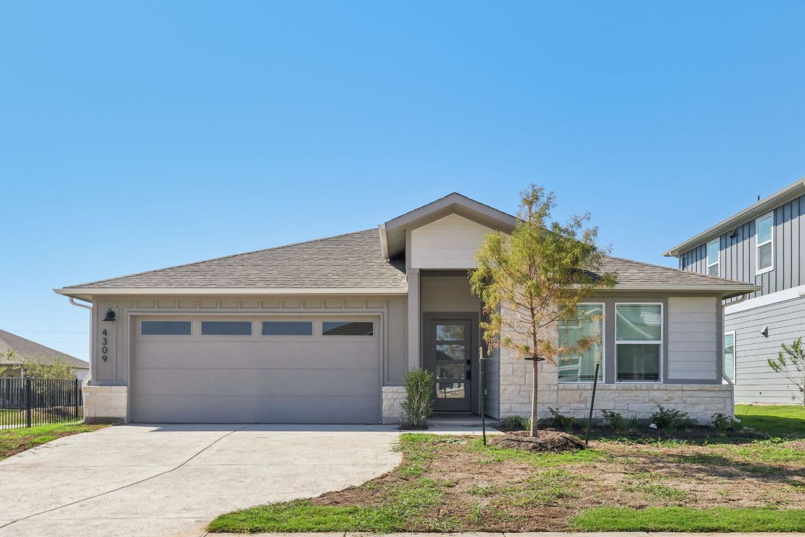 View of front of property with stone siding, a shingled roof, an attached garage, and driveway