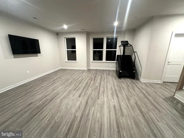 a view of empty room with wooden floor and windows